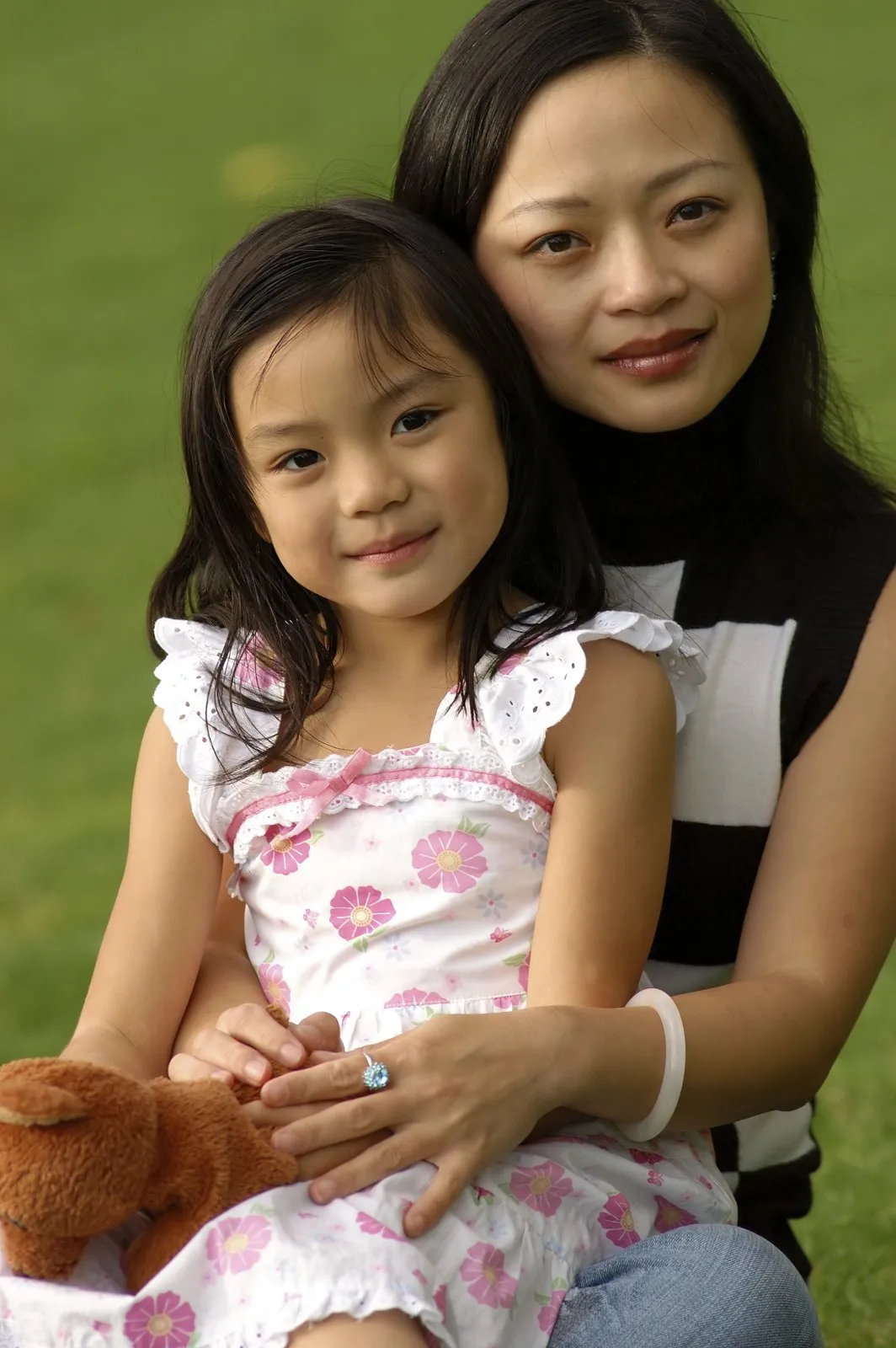 A mother and her young daughter sitting together outdoors
